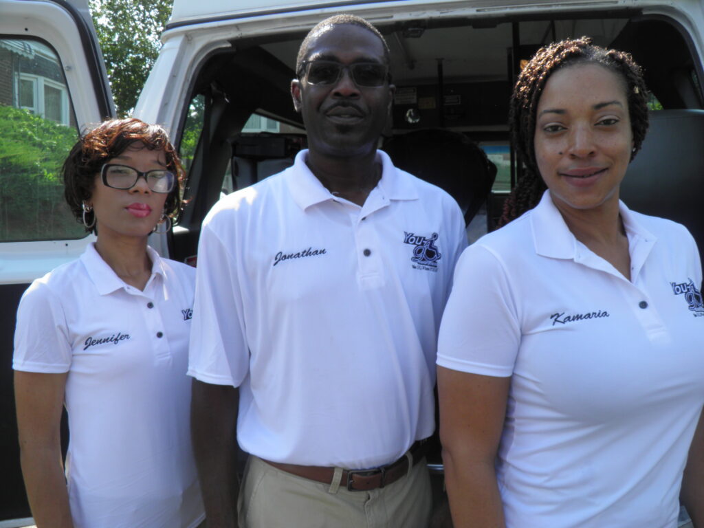 Three people in white polo shirts by van